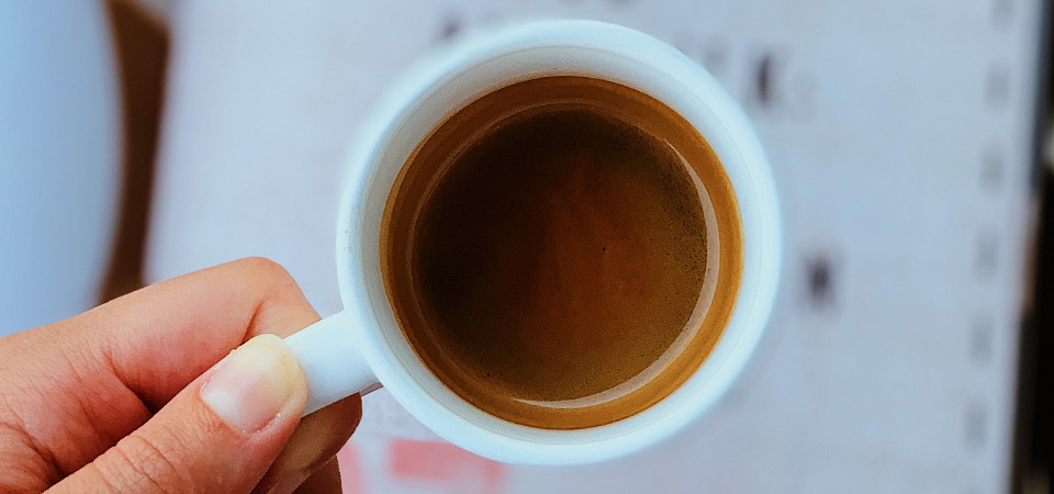 A fancy, rustic looking cup, filled with an espresso shot with added foam on top